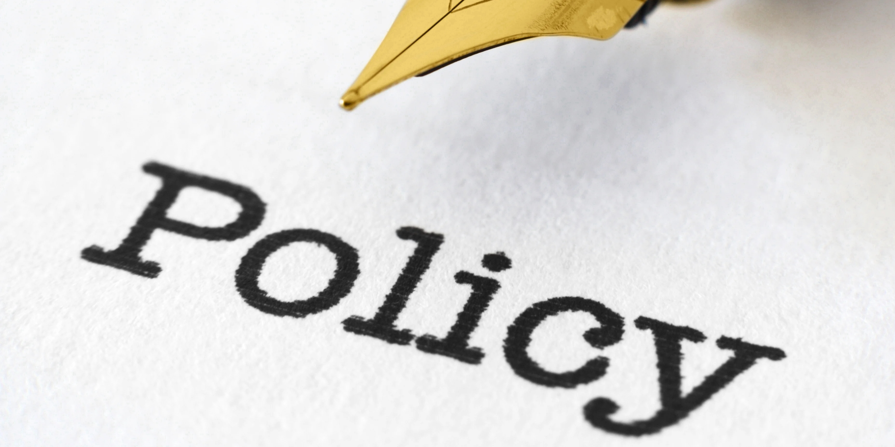 Fountain pen on white paper with the word “Policy” printed on the paper.